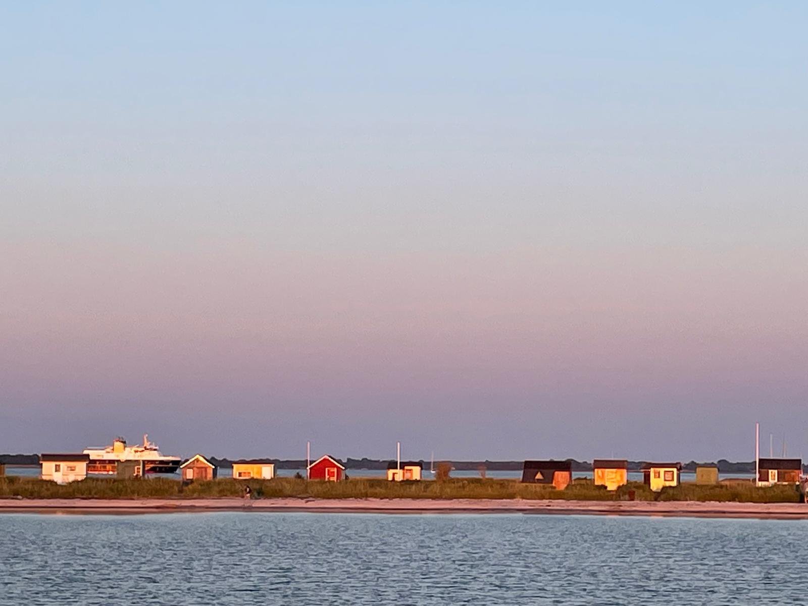 Bunte Badeh&auml;uschen am Strand auf &AElig;r&oslash; bei Sonnenuntergang