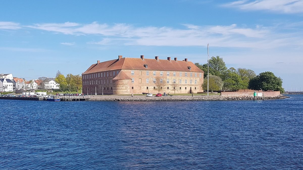 Schloss S&oslash;nderborg am Wasser unter blauem Himmel