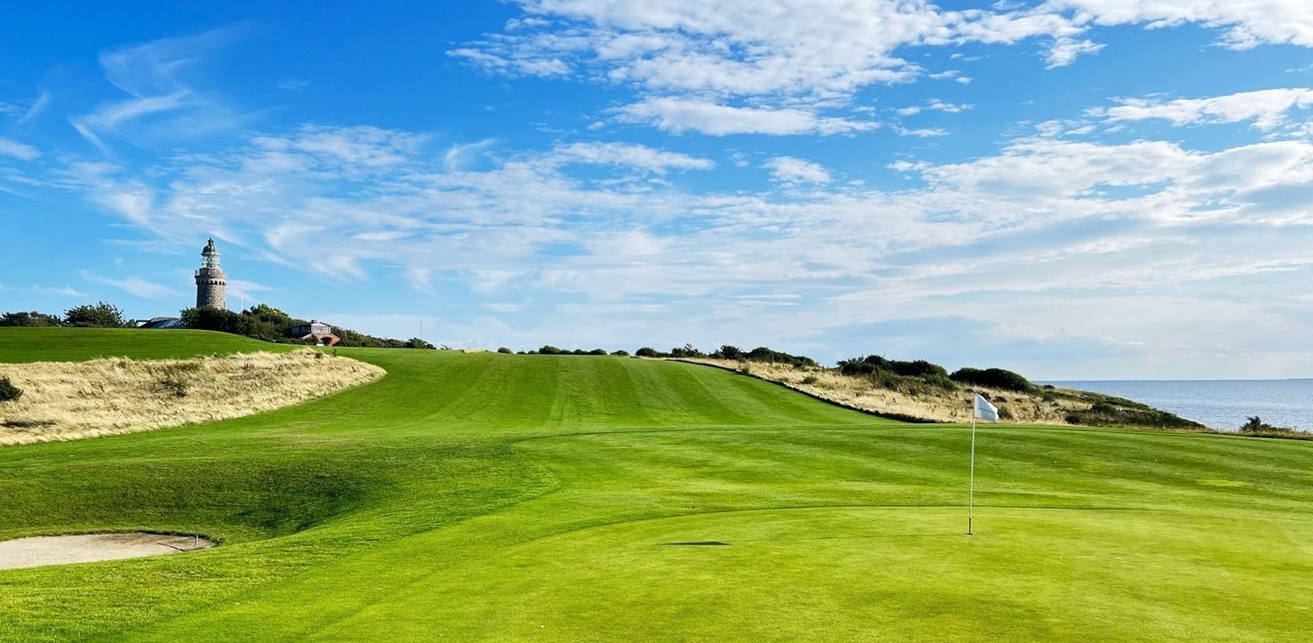Gr&uuml;n des &AElig;r&oslash; Golf Klub mit Fahne und Leuchtturm im Hintergrund