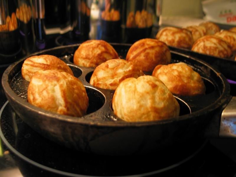 Goldbraune Æbleskiver in einer gusseisernen Æbleskiver-Pfanne