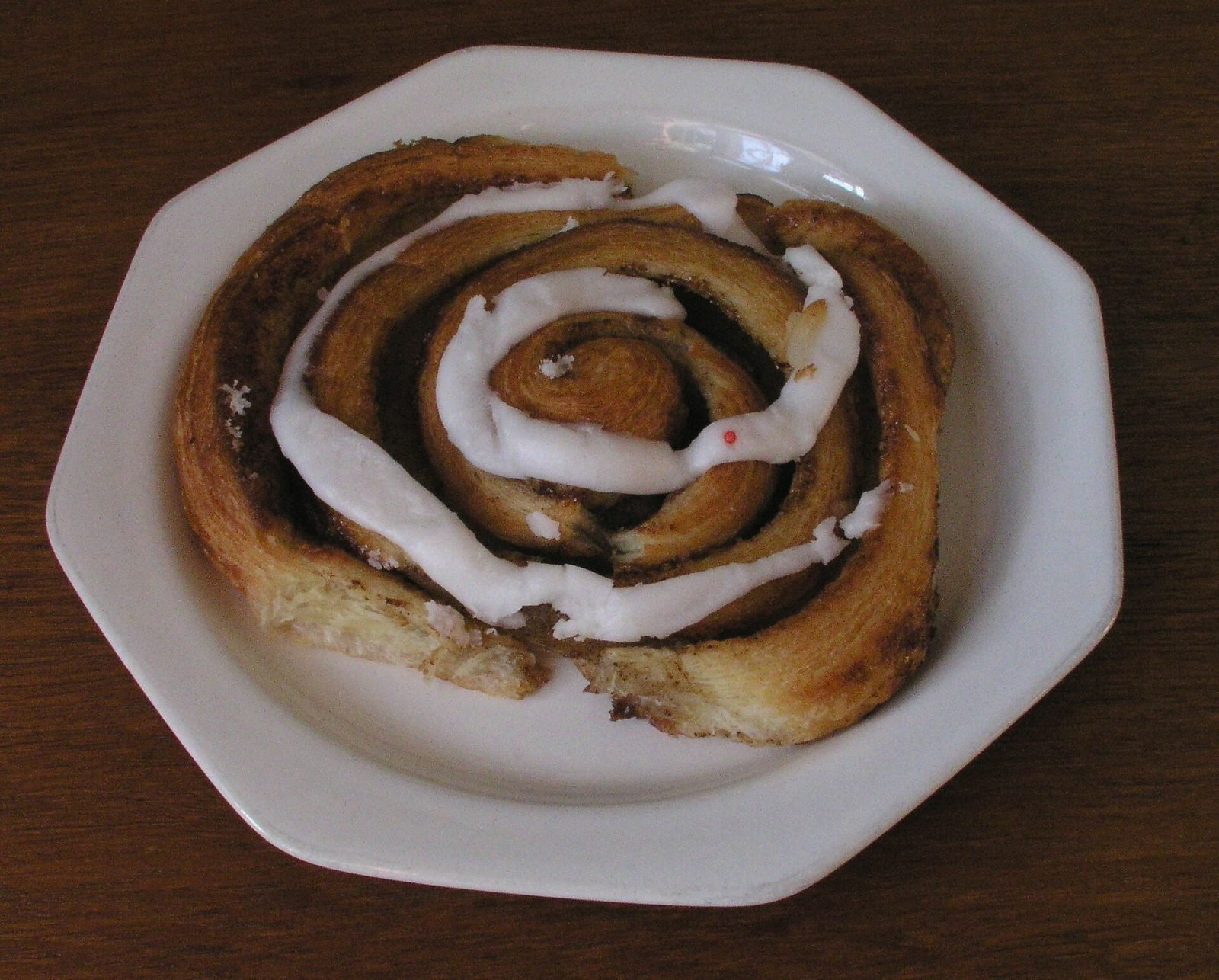 D&auml;nische Zimtschnecke mit Zuckerguss auf einem wei&szlig;en Teller