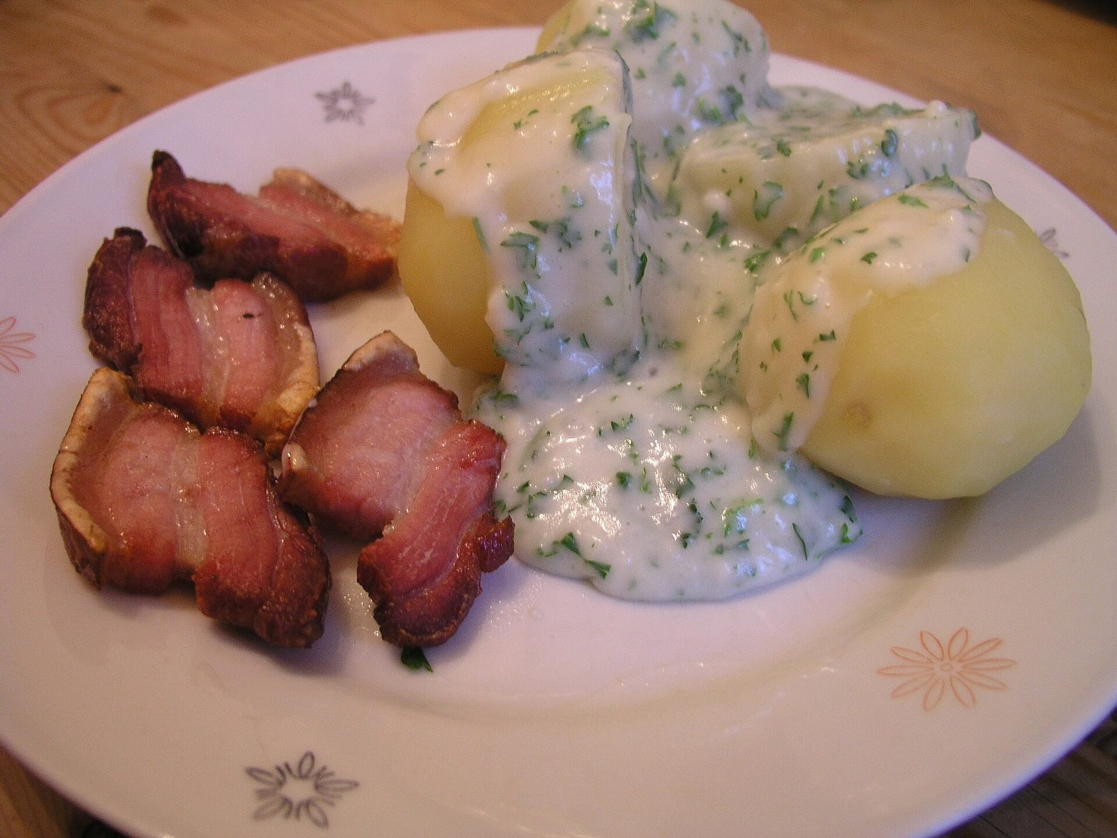 Gebratene Scheiben Schweinebauch mit Kartoffeln und Petersiliensauce auf einem weißen Teller